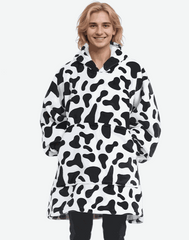 SNUGLFIT™ Hoodie Blanket in cow print worn by a person; cozy, oversized design for ultimate warmth and style.